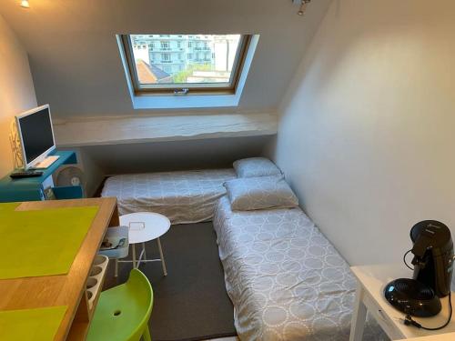 Cette petite chambre comprend un lit, un bureau et une fenêtre. dans l'établissement le duplex de Notre Dame, à Annecy