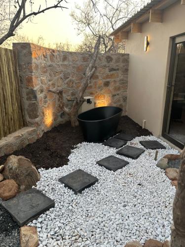 a garden with a bath tub and a stone wall at Oase by 7 Star Lodges - Greater Kruger Private 530ha Reserve in Hoedspruit