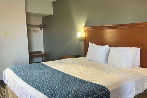 a hotel room with a large bed with a wooden headboard at Travelodge by Wyndham Terre Haute in Terre Haute