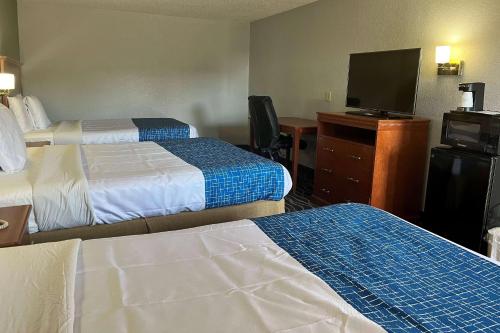 a hotel room with two beds and a flat screen tv at Travelodge by Wyndham Terre Haute in Terre Haute