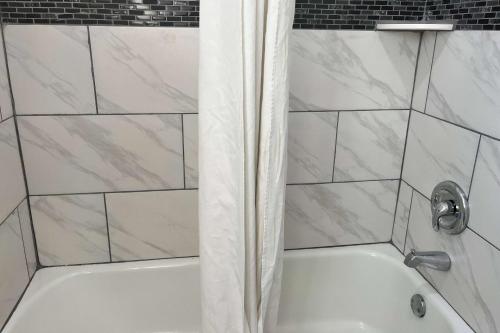 a bath tub with a shower curtain in a bathroom at Travelodge by Wyndham Terre Haute in Terre Haute