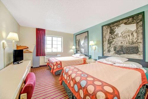 a hotel room with two beds and a television at Super 8 by Wyndham San Antonio/Fiesta in San Antonio