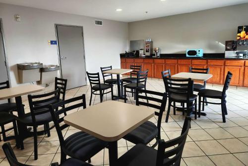 a restaurant with tables and chairs and a kitchen at Days Inn & Suites by Wyndham Thibodaux in Thibodaux