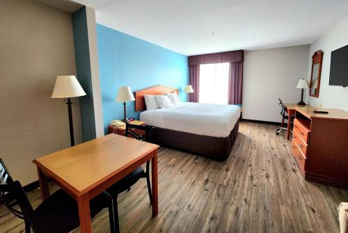 a hotel room with a bed and a desk and a table at Days Inn & Suites by Wyndham Thibodaux in Thibodaux