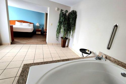 a bath tub in a bathroom with a bedroom at Days Inn & Suites by Wyndham Thibodaux in Thibodaux