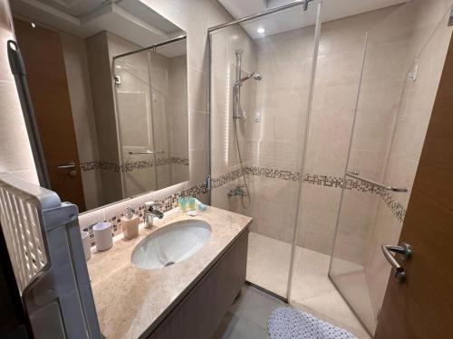 a bathroom with a sink and a glass shower at NA HARF108 Stylish Studio - YAS Island in Abu Dhabi