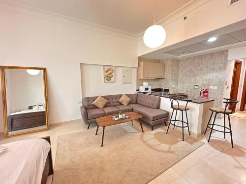 a living room with a couch and a table and a kitchen at NA HARF108 Stylish Studio - YAS Island in Abu Dhabi