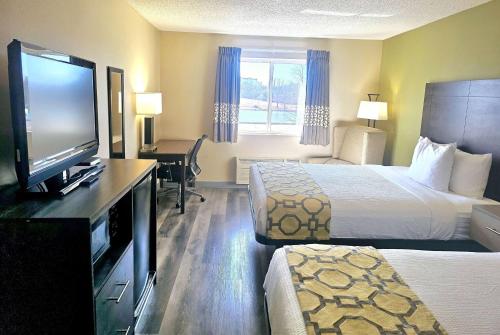 a hotel room with two beds and a flat screen tv at Baymont by Wyndham Rolla in Rolla