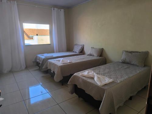 a room with three beds and a window at Apartamento completo in Montes Claros
