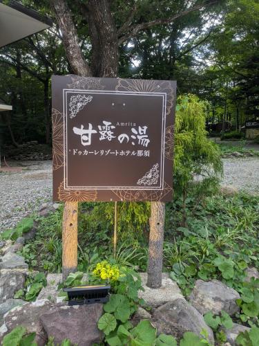a sign with asian writing on it in a park at ドゥカーレリゾートホテル那須甘露の湯 in Nasu-yumoto
