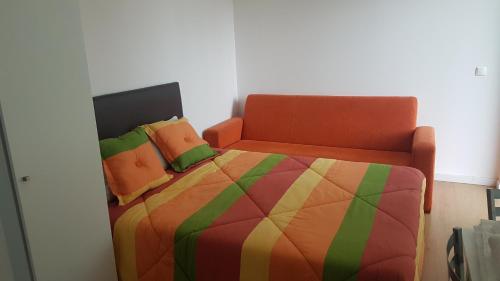 a bedroom with a colorful bed with an orange chair at Bungalows Land'shause in Pataias