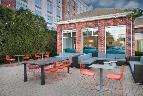 a patio with red chairs and tables and a building at Hilton Garden Inn Hoffman Estates in Hoffman Estates