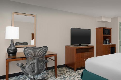 a hotel room with a desk with a chair and a television at Hilton Garden Inn Hoffman Estates in Hoffman Estates
