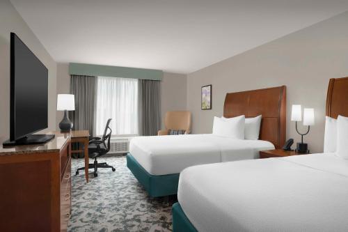 a hotel room with two beds and a flat screen tv at Hilton Garden Inn Hoffman Estates in Hoffman Estates