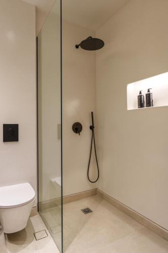 a bathroom with a glass shower stall and a toilet at Halo Santorini - Living Experience in Fira