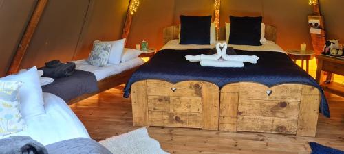 a bedroom with a large bed and two bedsskirts at Scaldersitch Farm Boutique Glamping Tipi with private wood fired hot tub in Sheen