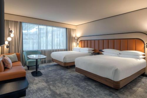 a hotel room with two beds and a chair at Hilton Paris La Défense in Puteaux