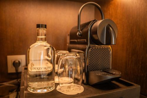 a bottle of alcohol and two glasses on a counter at Dukes' Arches Brugge - by Dukes' Hotel Collection in Bruges