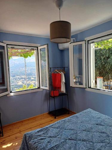 a bedroom with blue walls and windows with a bed at Kefalonia Alexis house in Pilaroú