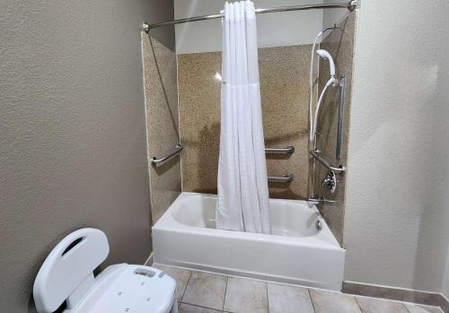 a bathroom with a shower and a toilet and a tub at Days Inn by Wyndham Kemah in Kemah