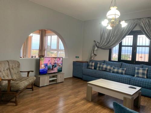 Una sala de estar con un sofá azul y un televisor. en Villa Cabonegro UNIQUEMENT POUR FAMILLES, en Cabo Negro