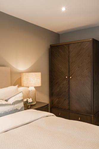 a bedroom with a large wooden cabinet next to a bed at The Orchard, 5 Star Luxury Accommodation in Newcastle