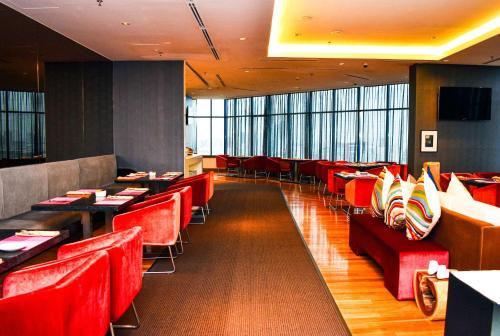 a restaurant with red chairs and tables and windows at Wyndham Grand Bangsar Kuala Lumpur in Kuala Lumpur