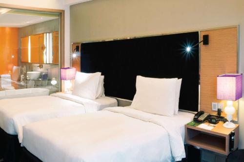 a hotel room with two beds and a telephone at Wyndham Grand Bangsar Kuala Lumpur in Kuala Lumpur