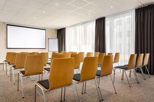 a conference room with chairs and a projection screen at Wyndham Garden Munich Messe in Munich