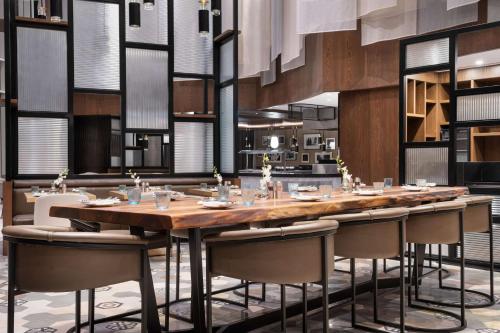 Hilton Riyadh Olaya في الرياض: غرفة طعام كبيرة مع طاولة طويلة وكراسي