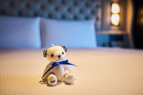 a small teddy bear sitting on a bed at Hilton Yokohama in Yokohama
