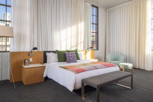 a hotel room with a large bed and a chair at Fordson Hotel, in the Unbound Collection by Hyatt in Oklahoma City