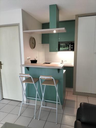 une cuisine avec des placards verts, un comptoir et des tabourets dans l'établissement Aude, à La Rochelle