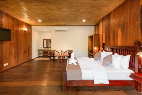 a bedroom with a large white bed and a table at Tiny Home in Phumi Ta Phul