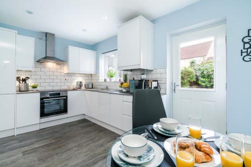 a kitchen with white cabinets and a table with food at Progressive House 5 Bedrooms Inc Study with Sofabed, Garden, Smart TV in Every Bedroom FREE Parking in Peterborough
