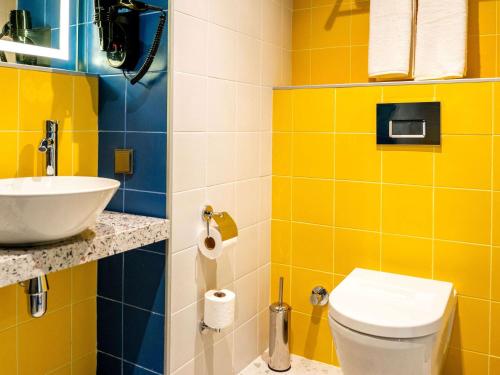 a yellow bathroom with a sink and a toilet at ibis Styles Batumi Hotel in Batumi
