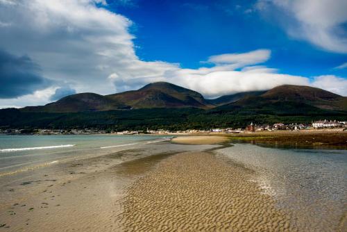 a sandy beach with mountains in the background with a town and the ocean at The Orchard, 5 Star Luxury Accommodation in Newcastle