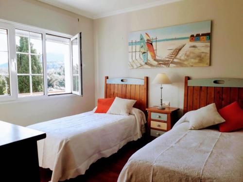 zwei Betten in einem Zimmer mit zwei Fenstern in der Unterkunft Vivienda Vacacional El Cuetu del Sella in Llames de Pría