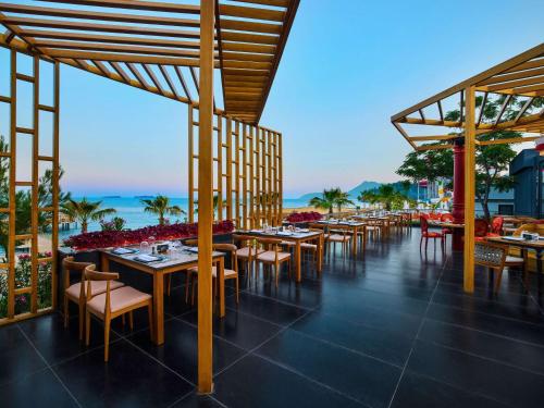 a restaurant with tables and chairs and the ocean at Mövenpick Resort Antalya Tekirova - Ultra All Inclusive in Tekirova