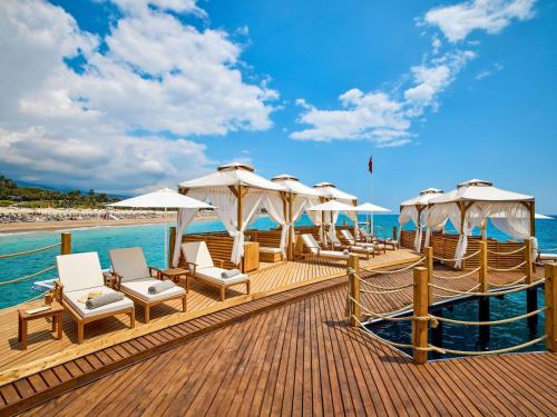 a deck with chairs and umbrellas on a beach at Mövenpick Resort Antalya Tekirova - Ultra All Inclusive in Tekirova