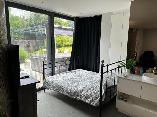 a bedroom with a bed and a large glass window at Tranquilo Maaseik in Maaseik