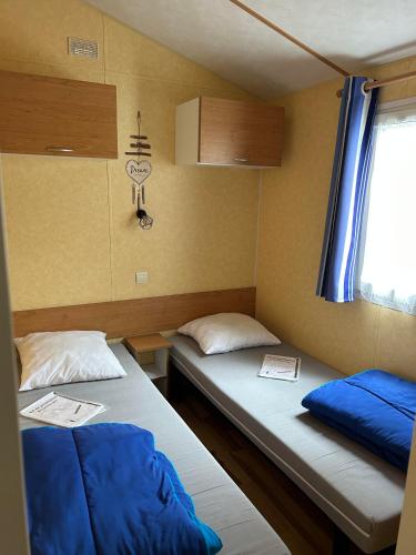 deux lits dans une petite pièce avec une fenêtre dans l'établissement Jolie mobil home à louer, à Thiviers