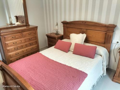 a bedroom with a bed with two red pillows at Na orixe in Rianjo