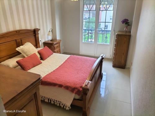 a bedroom with a bed with a red blanket at Na orixe in Rianjo