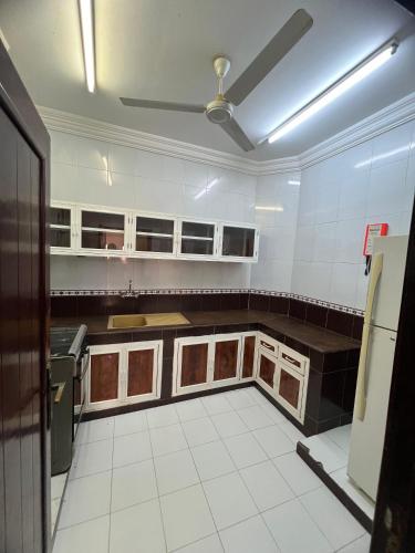 a large kitchen with white tiles and brown cabinets at RED-14 Al Ferdous in Salalah