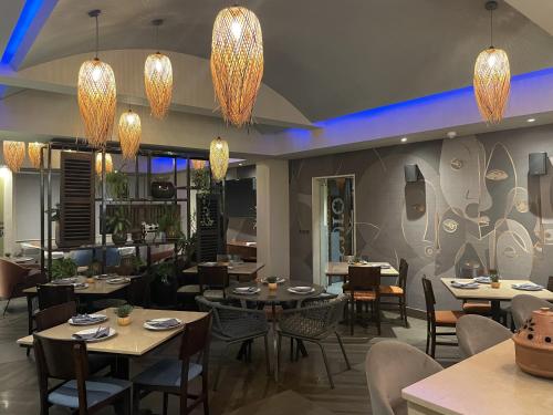 a restaurant with tables and chairs and chandeliers at Roots Hotel Apartment in Accra