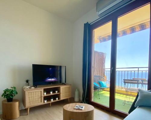 un salon avec une télévision et une grande fenêtre dans l'établissement VUE MER EXCEPTIONNELLE !! Studio calme et lumineux sur la prestigieuse route des Sanguinaires à Ajaccio, à Ajaccio