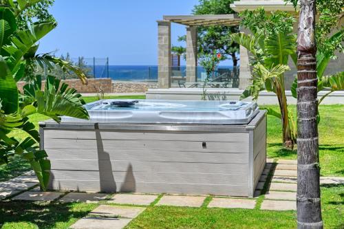 a hot tub sitting in the grass in a yard at Larimar Luxury Sea View Villa in Kissamos