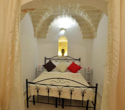 Schlafzimmer mit einem schwarzen Bett und roten Kissen in der Unterkunft Le Nicchie Ostuni in Ostuni