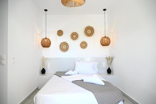 a white bedroom with a bed and some baskets at Beachfront cycladic suite Irene Apartments boutique hotel in Kanala